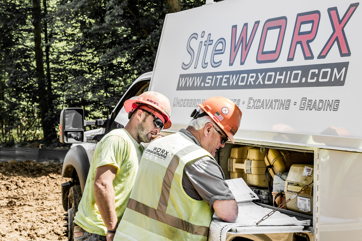 Two construction workers reviewing documents by a truck